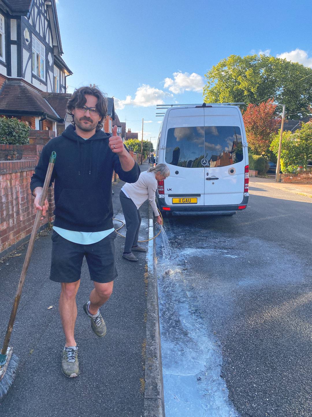Sam and his mum diluting paint splashed on the road.