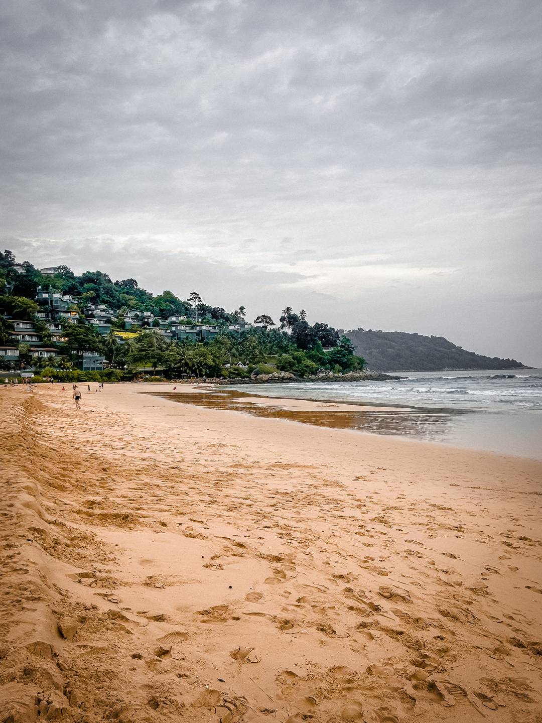 Golden sand beach and lush green forest on the cliffs in Phuket, Thailand