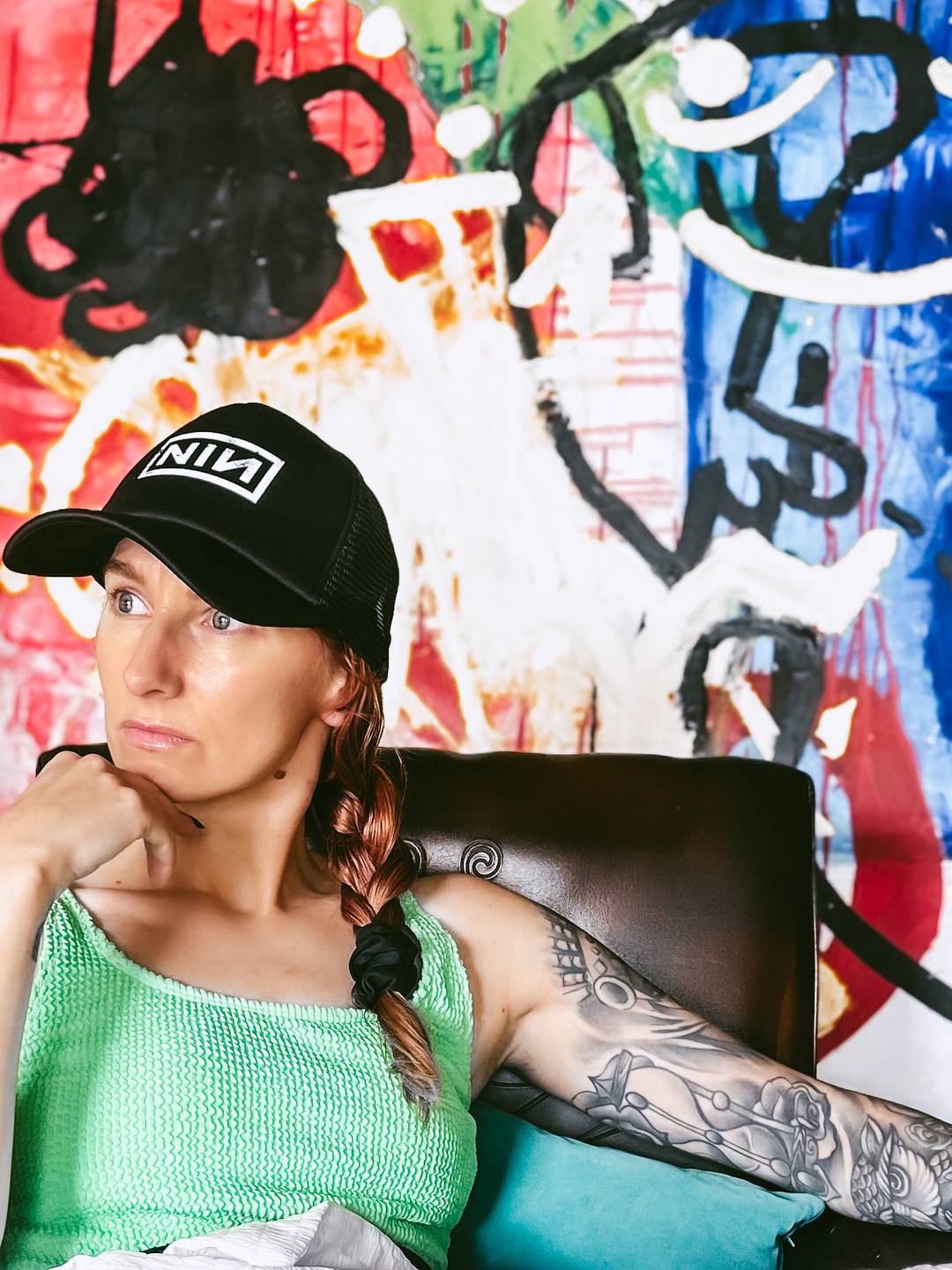 woman sat expresionless in front of grafiti art.