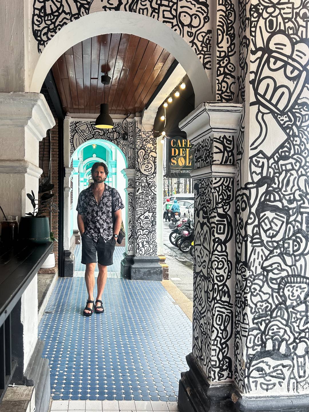 man walking through the black and white archway in Old Town, Phuket