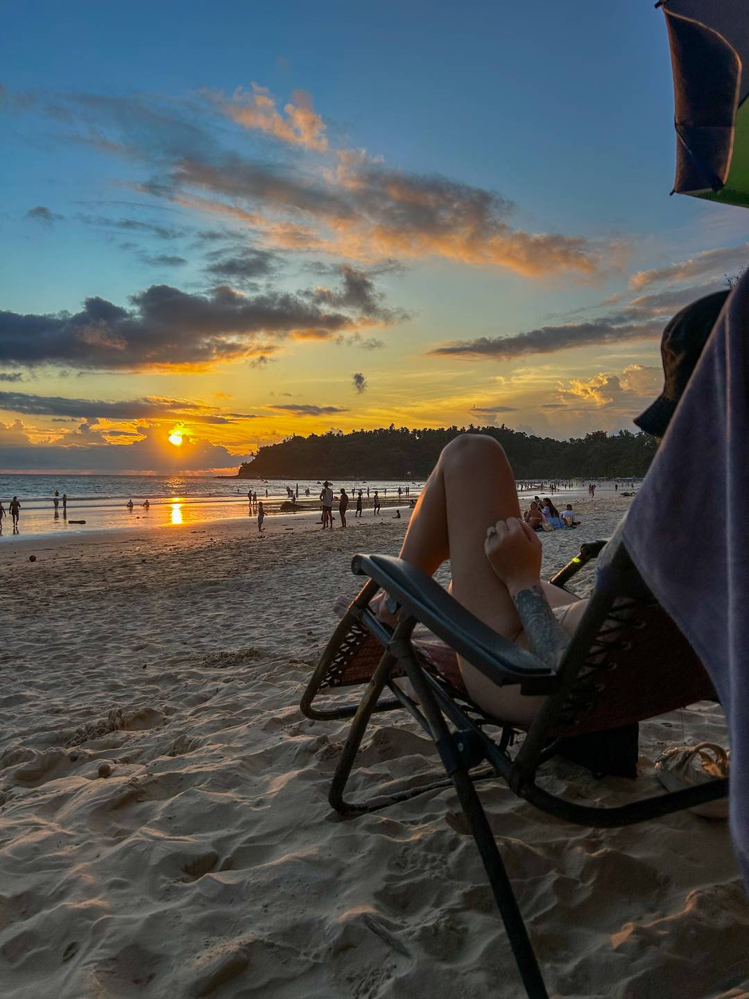 Woman sat on sun lounger at the beach at sunset.