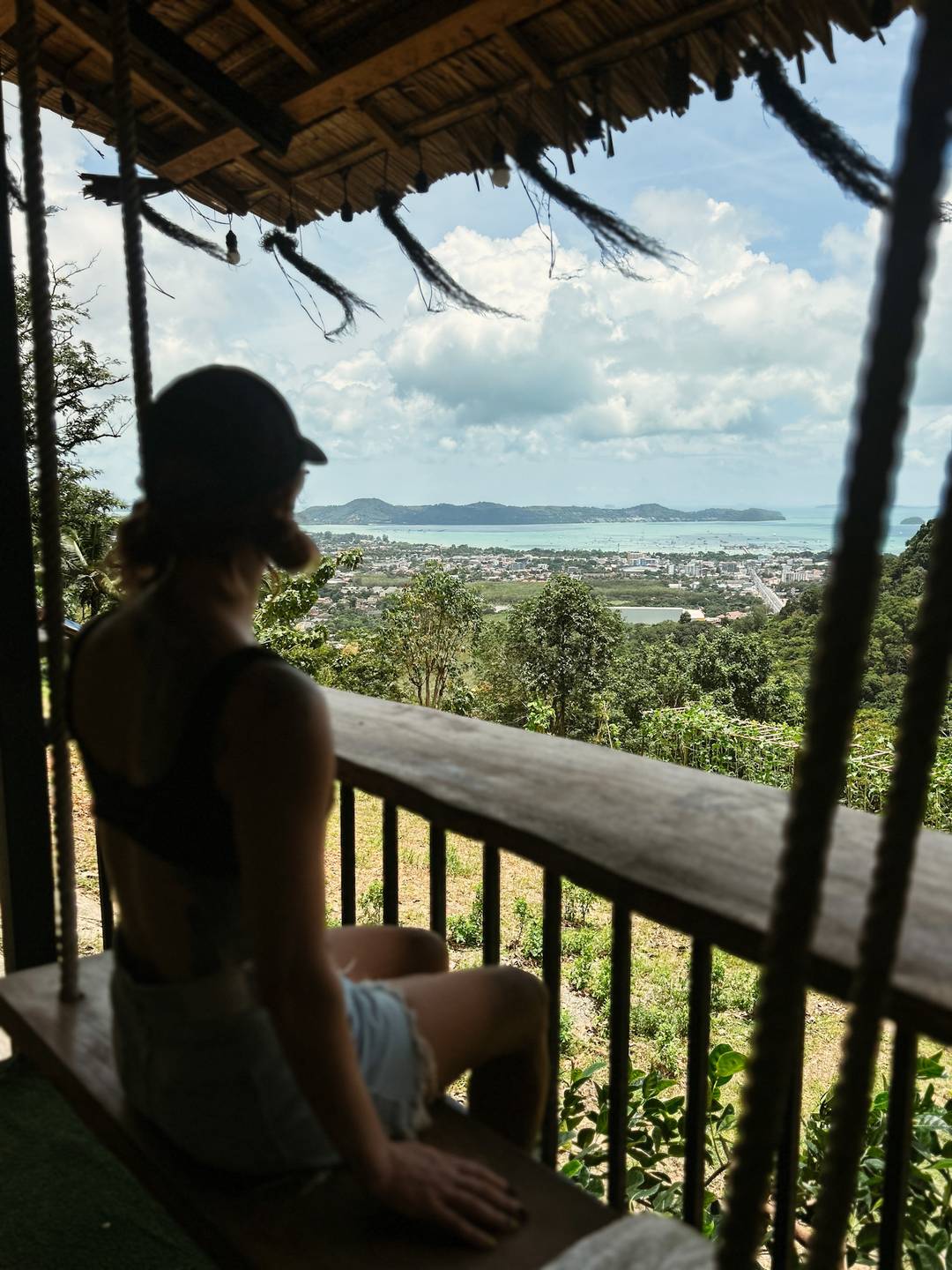 a silhouette of a women sitting staring at a view of the ocean in thailand 