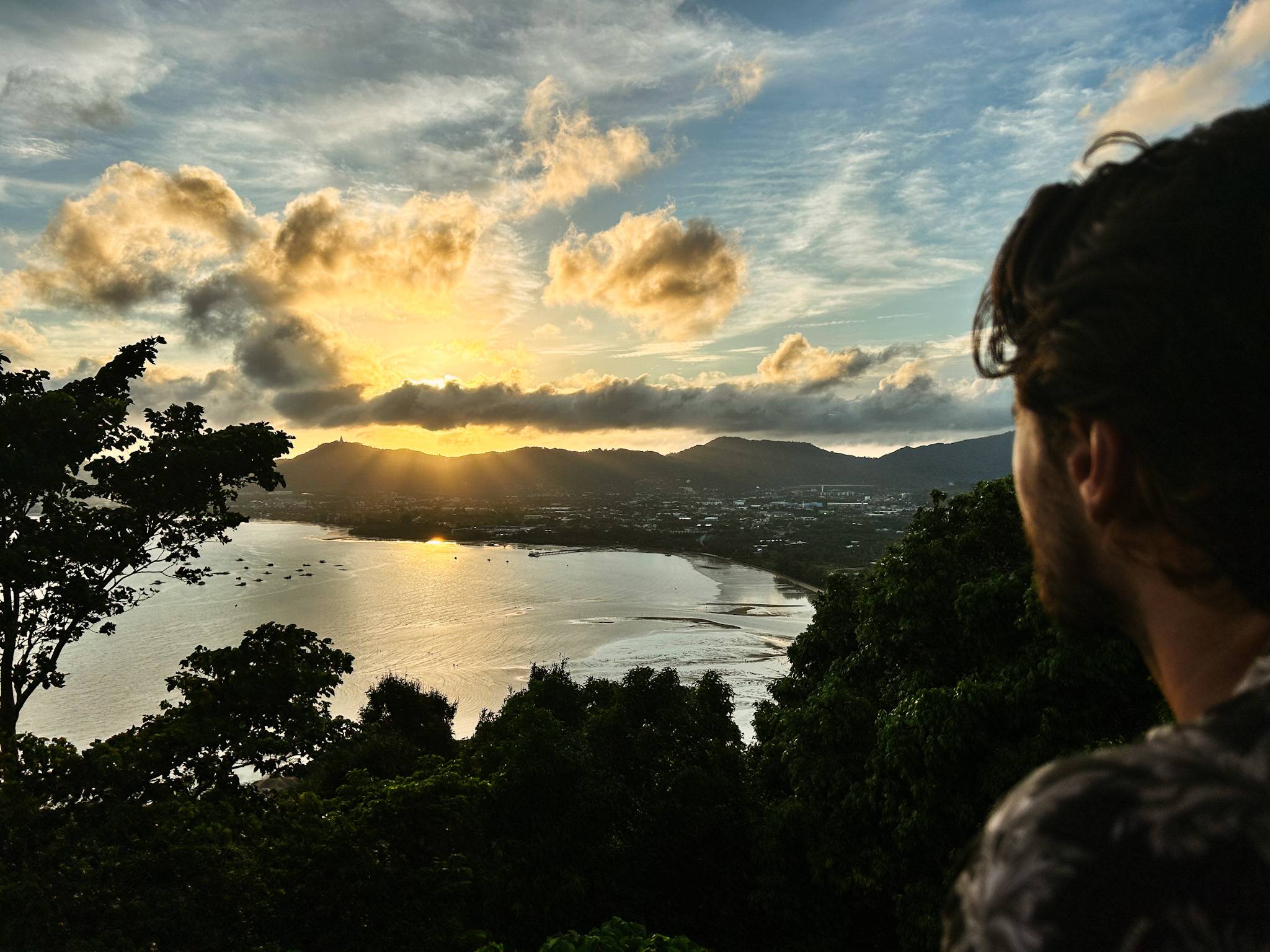 A man staring at a sunset over an ocean bay