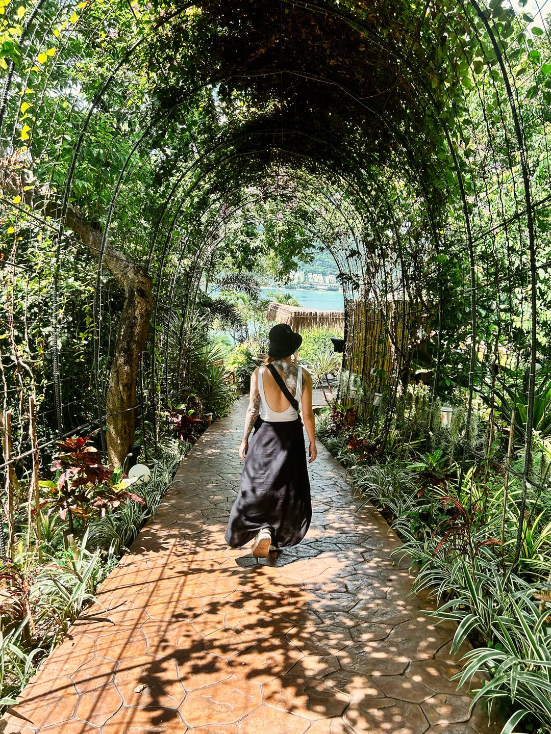 a women walking through a plant covered archway