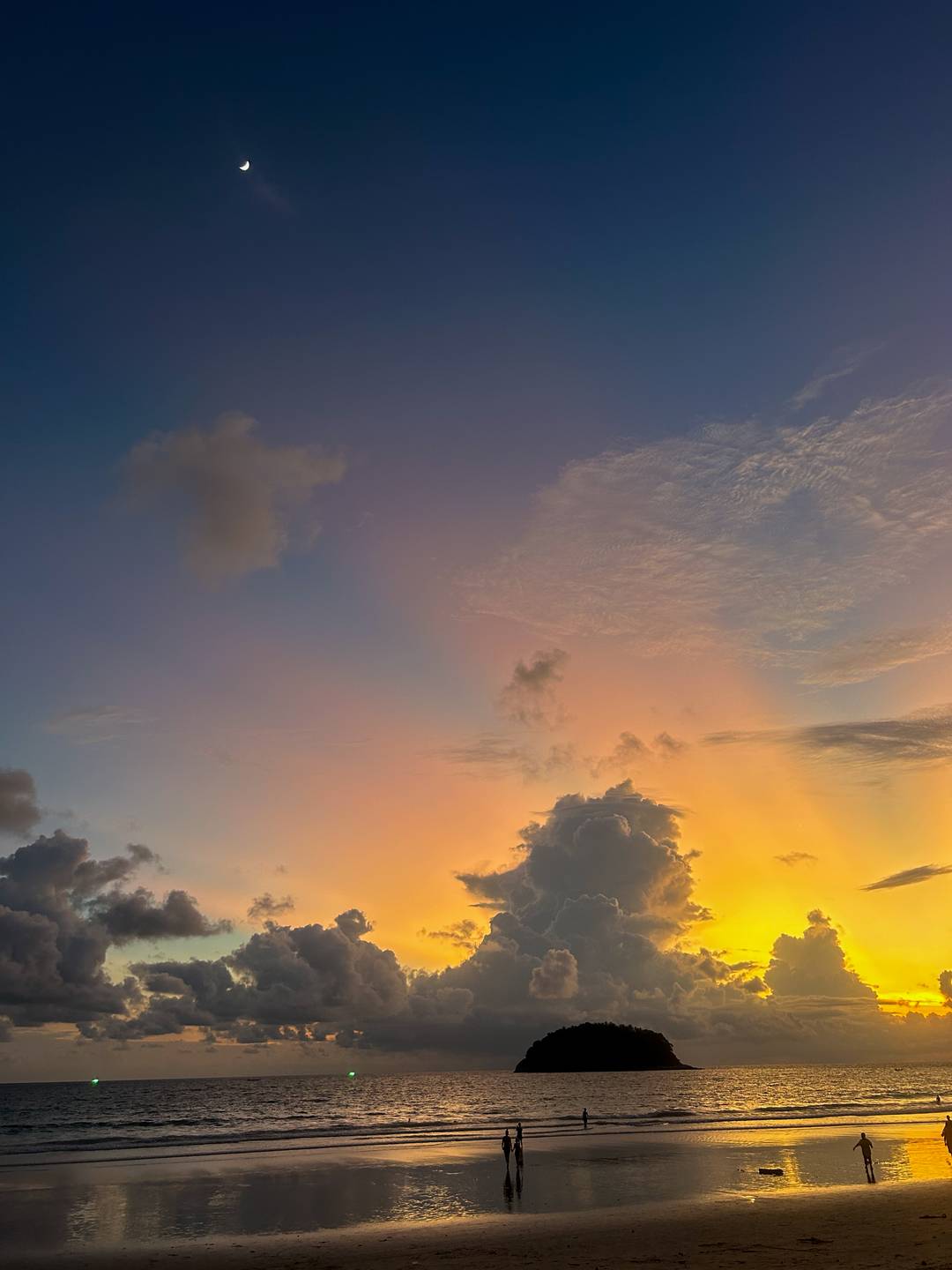 Pinks, blues, greens, peach, orange and yellow sunset behind the clouds at the beach in Phuket, Thailand.