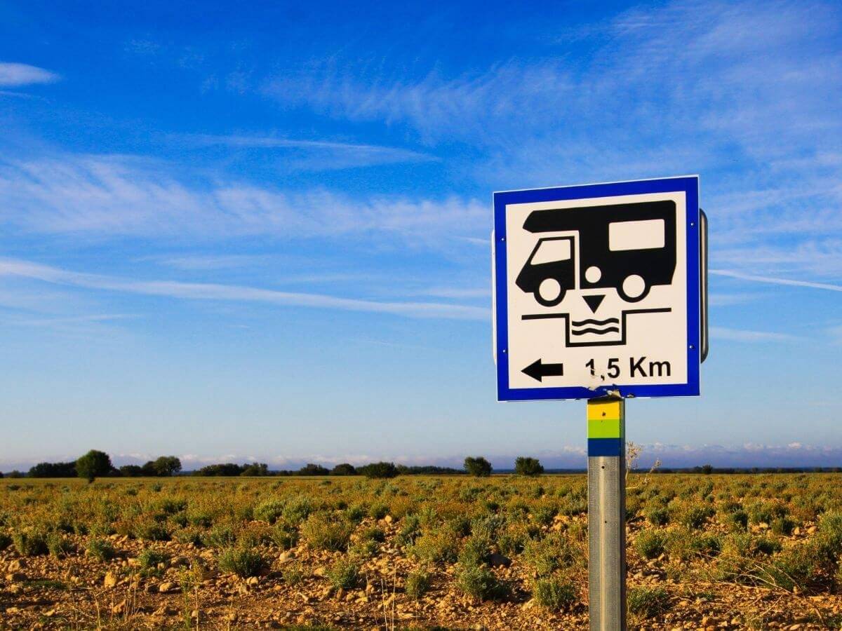 Campervan black water dumping sign at the side of a road on a blue sky day.