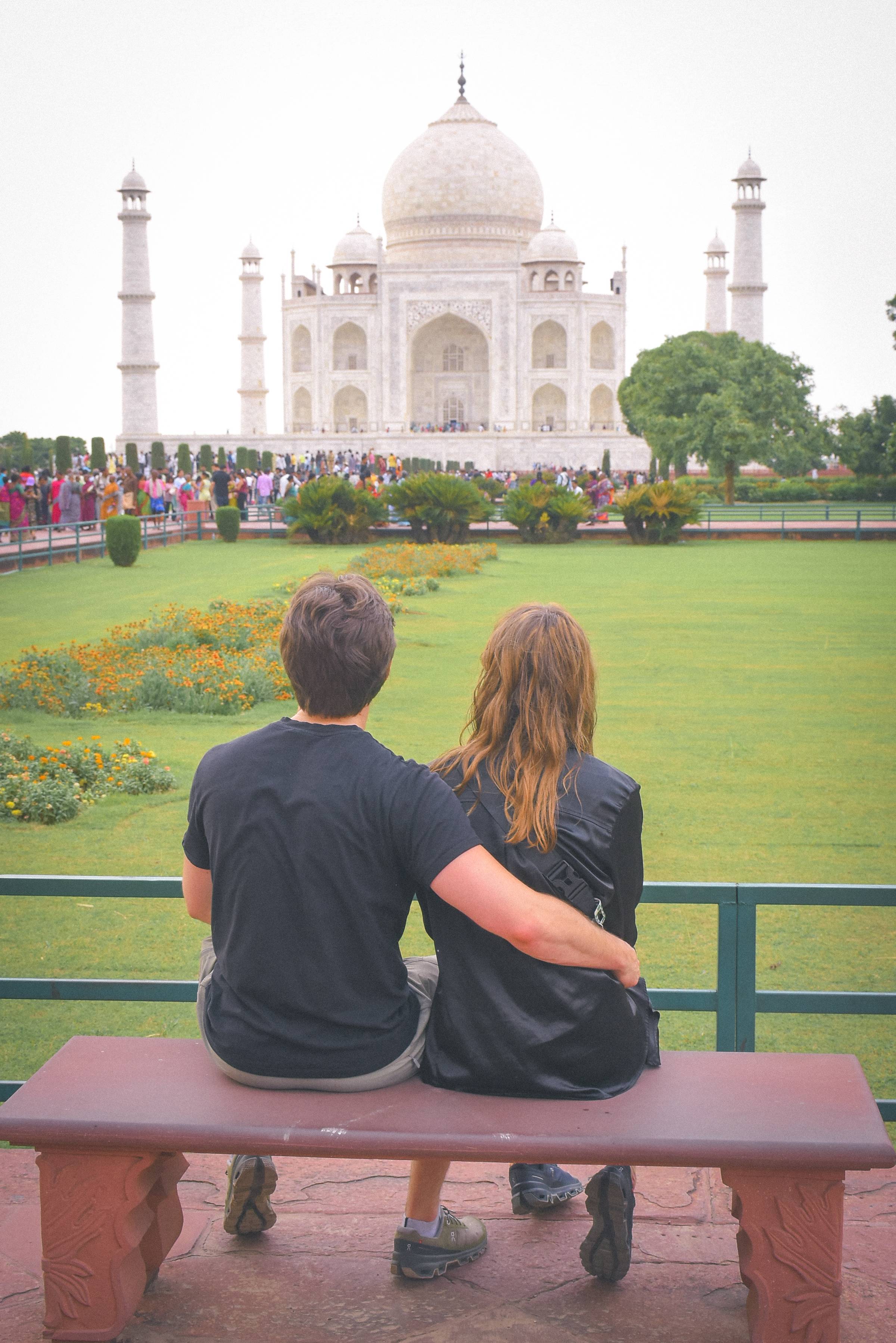 couple sat on a bench in front of the Taj Mahal