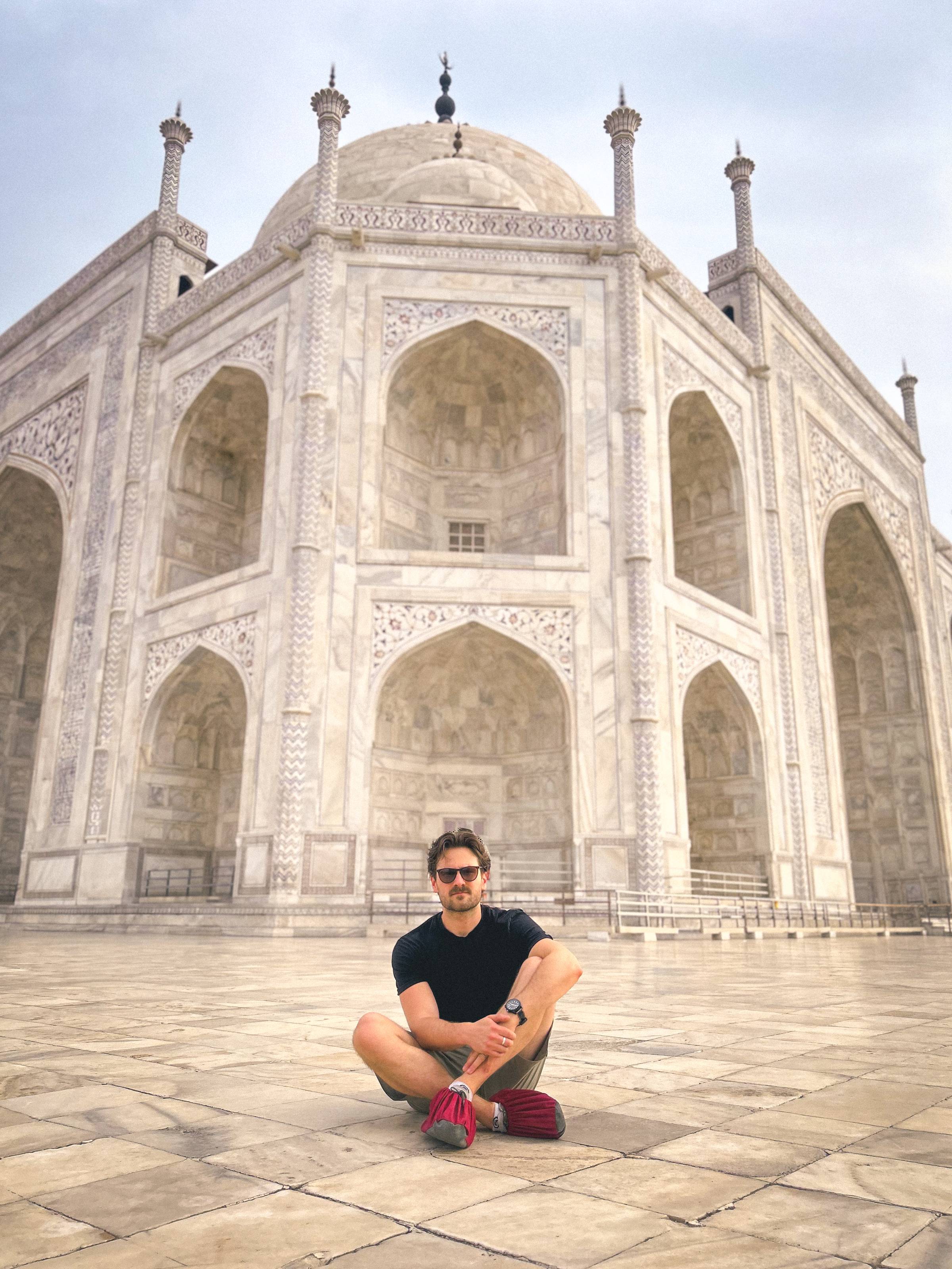 Man sat on the floor of the white marble at the Taj Mahal.