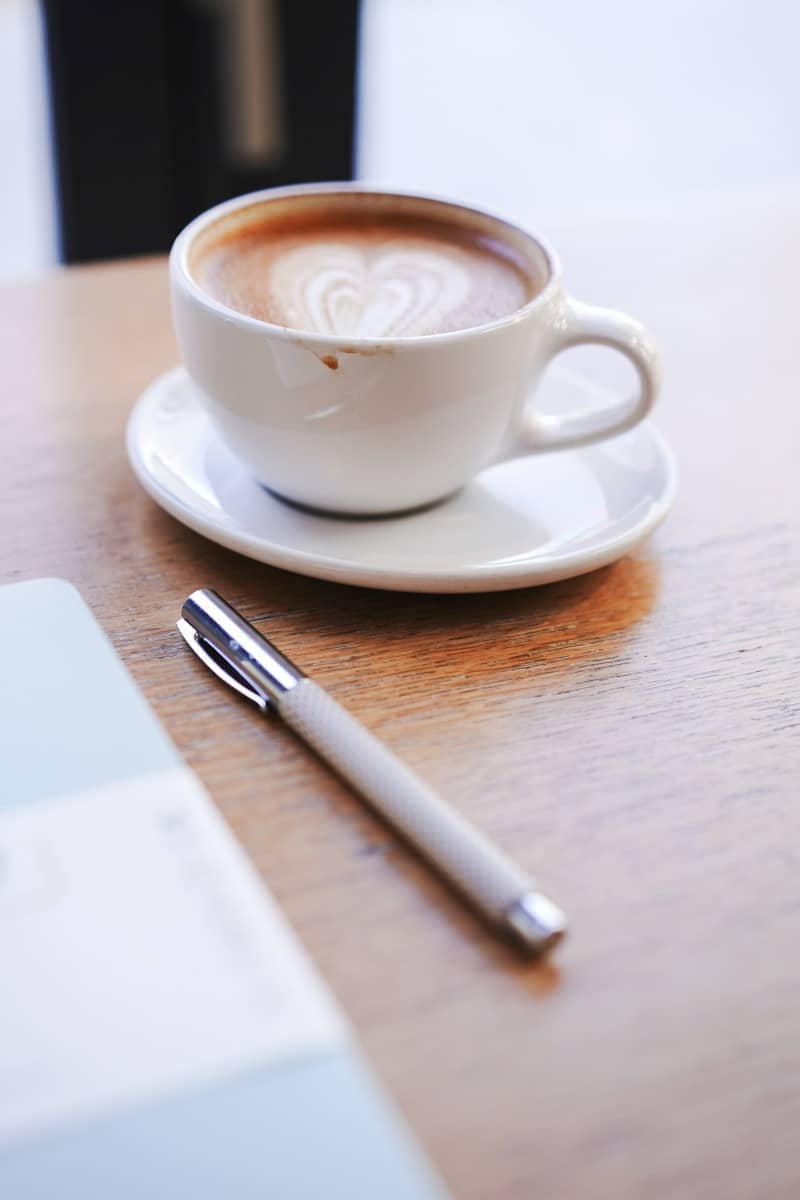 A cup of coffee with latte art and a pen.