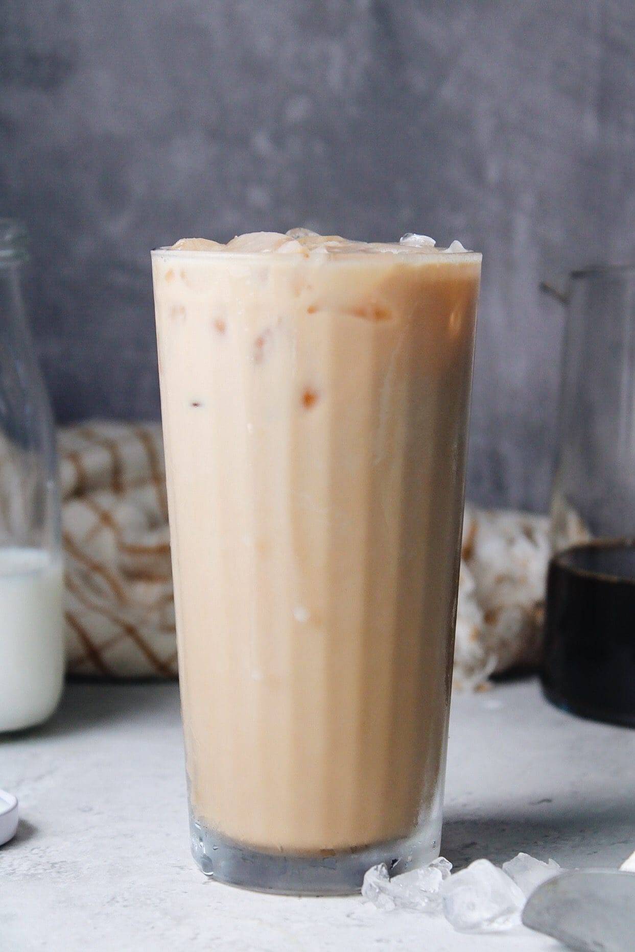 chai tea latte in a tall glass in front of a grey background
