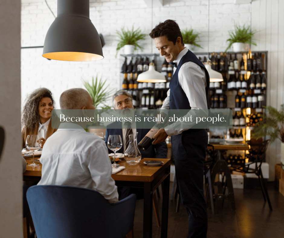 A member of a the waitstaff in a restaurant is presenting a bottle of wine to the table host and his guests.