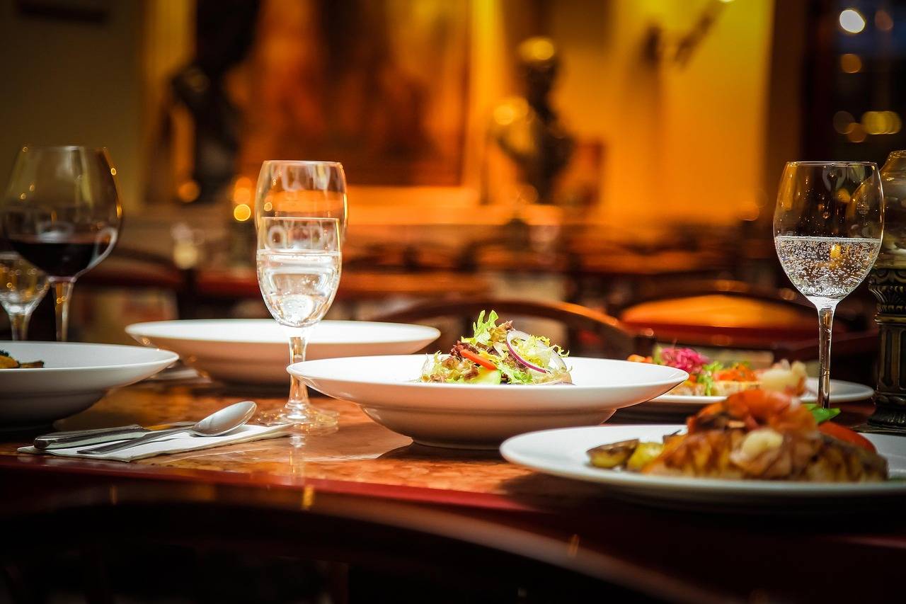 Two plates of food and wine glasses on a restaurant table.