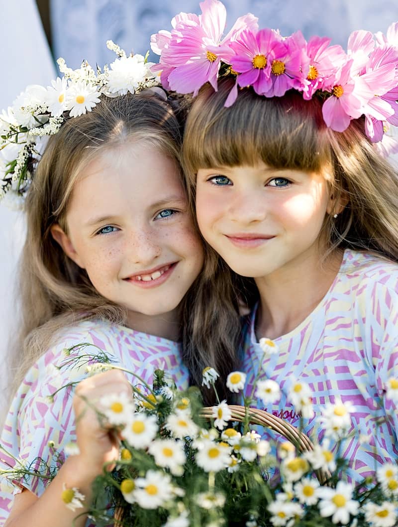 Two young girls wearing flower crowns and holding flowers