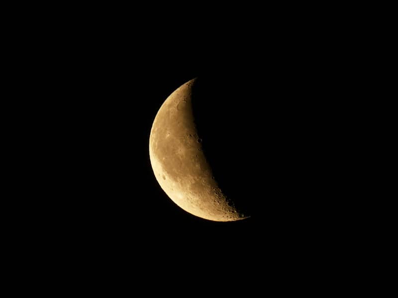 A crescent moon glows brightly in the night sky.