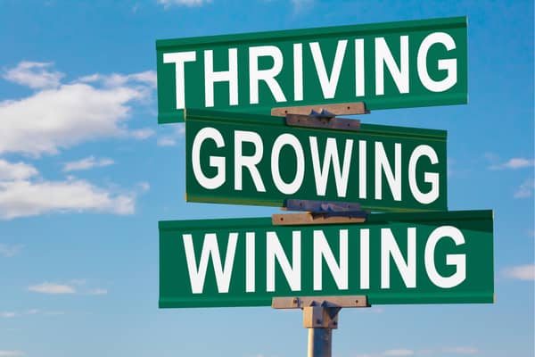 Street sign saying thriving, growing, winning