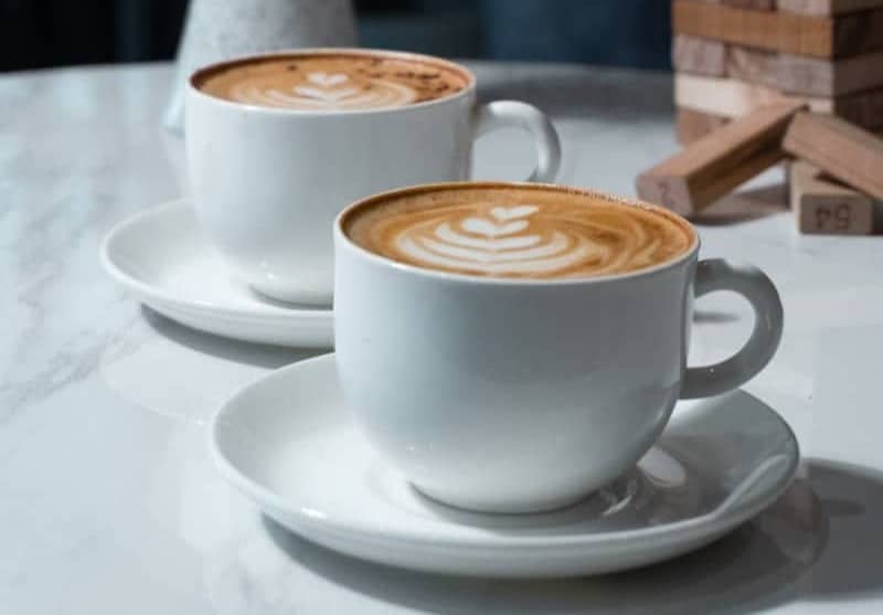 Two cups of coffee sit on a table