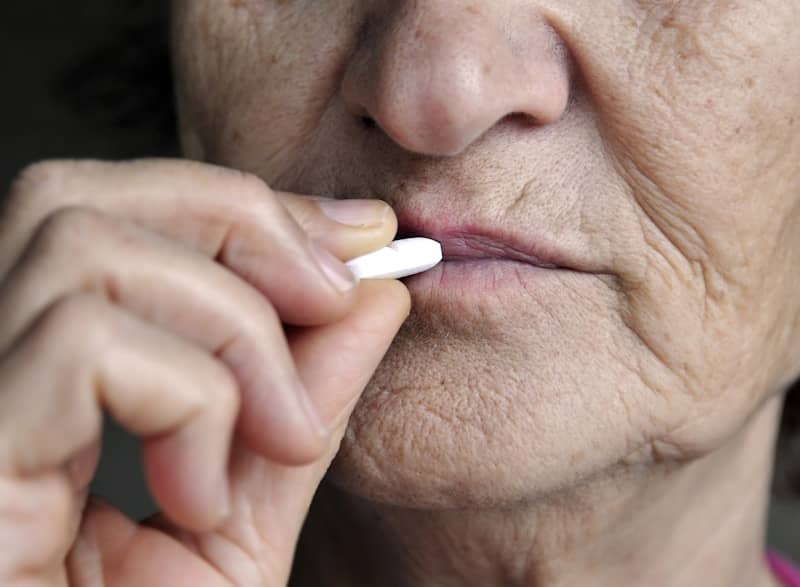 Elderly woman taking a white pill