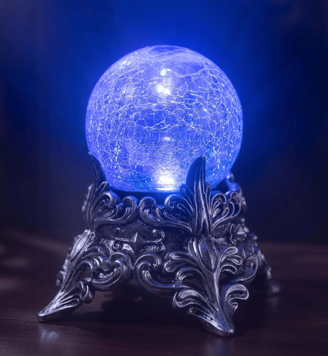 A crystal ball lit up in blue, on top of a short, ornate metal stand.