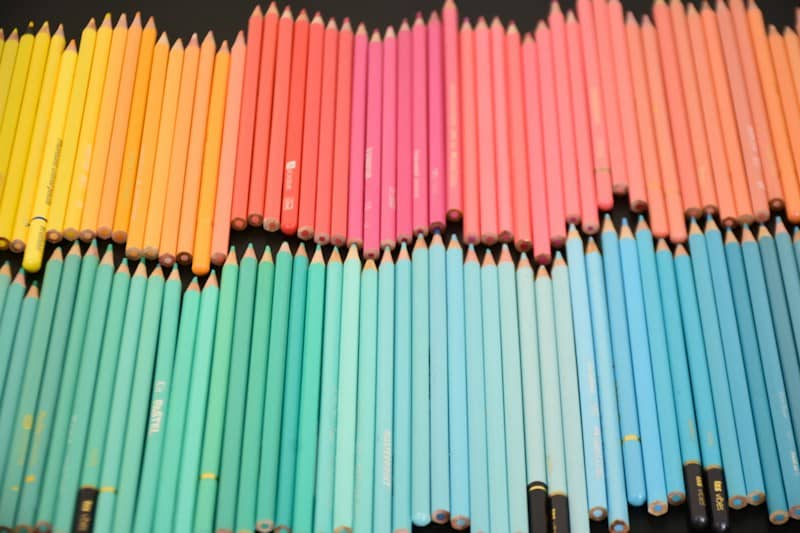 A large collection of colored pencils arranged in a gradient from yellow to blue