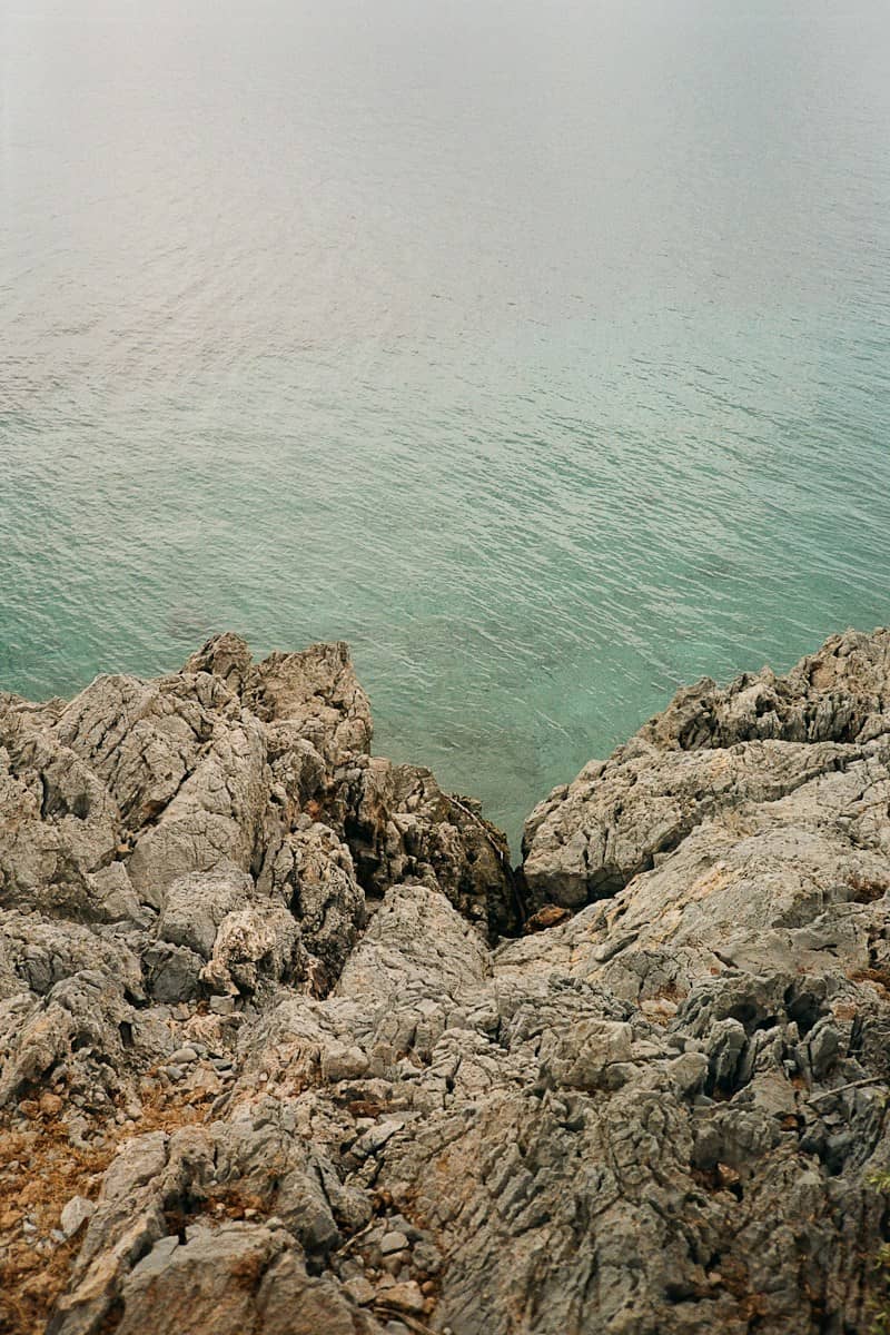 Jagged grey rocks overlooking the clear turquoise water of the Aegean Sea in Bodrum