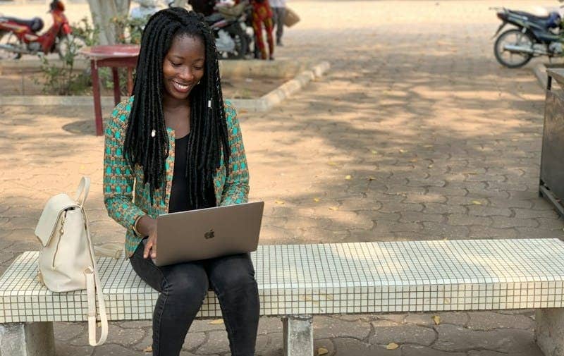 a person sitting on a bench with a laptop