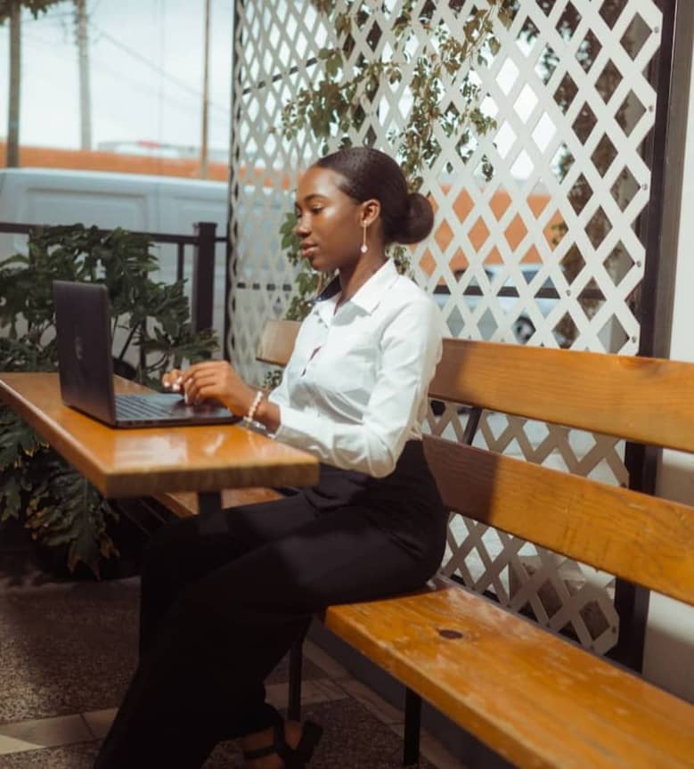 A woman works on her laptop at an outdoor cafe.