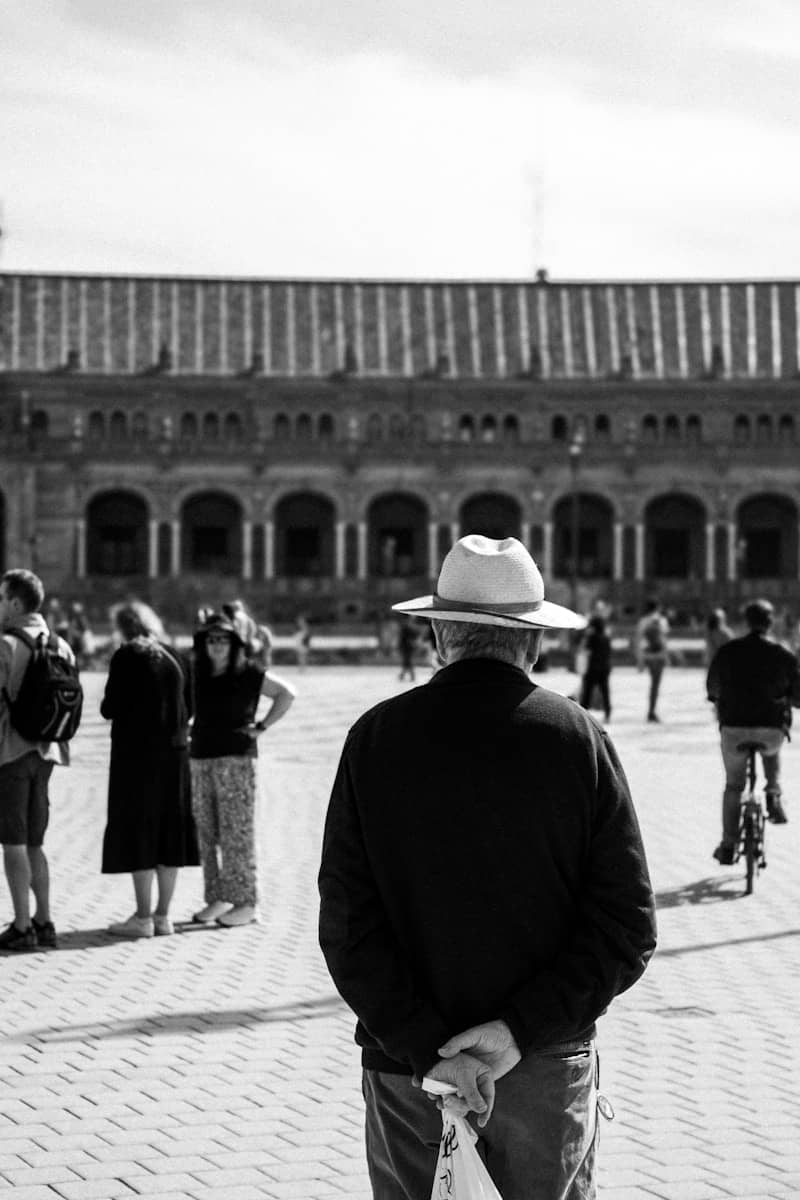 Man in hat stands in plaza with people