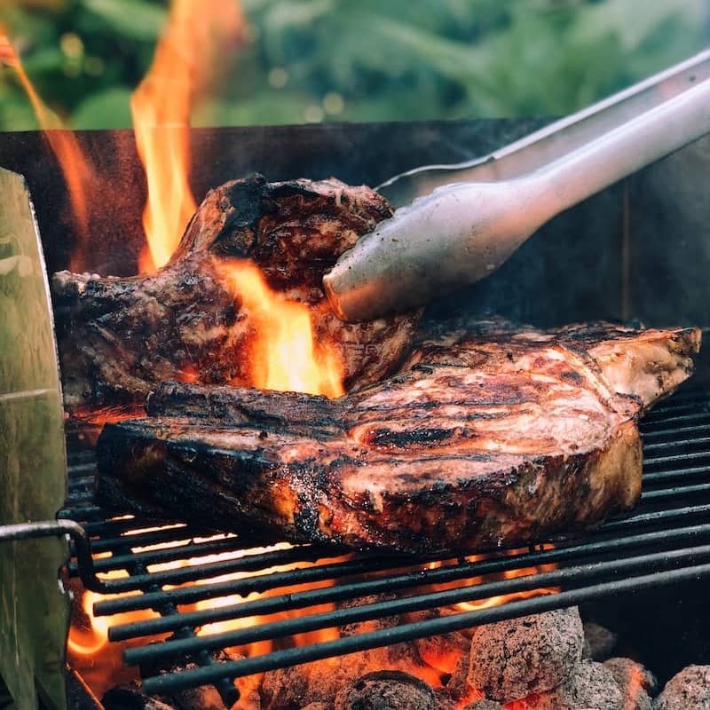 gray metal tong and grilled meat with fire