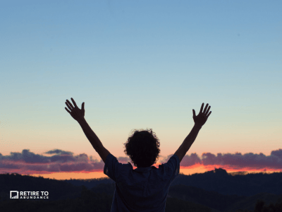 sunset with silhouette of person raising arms overhead