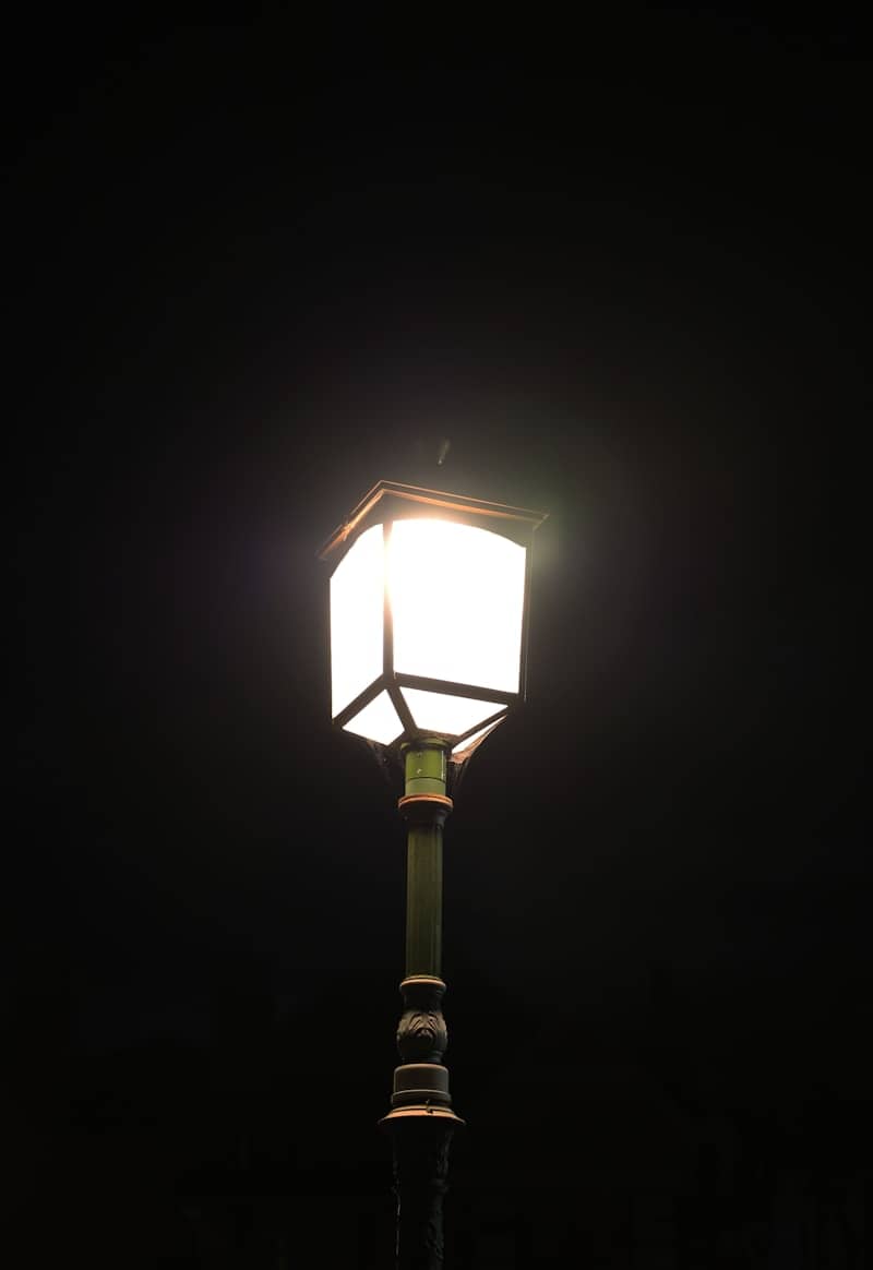 A vintage street lamp glows brightly at night.