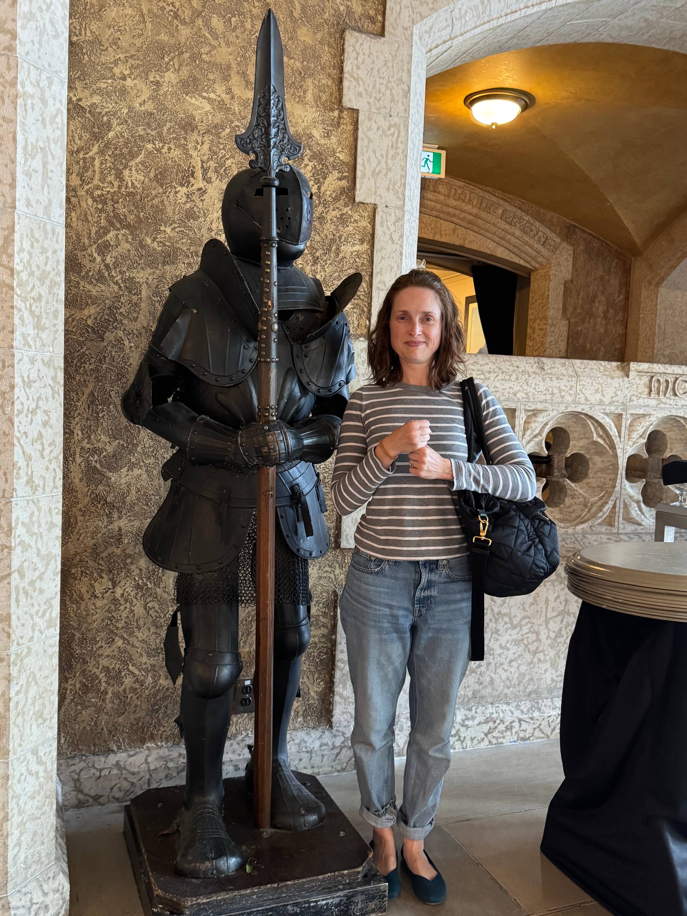 Lee poses next to a suit of armor, mimicking its pose