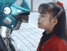 A little girl kisses a robot, whose eyes light up with apparent happiness