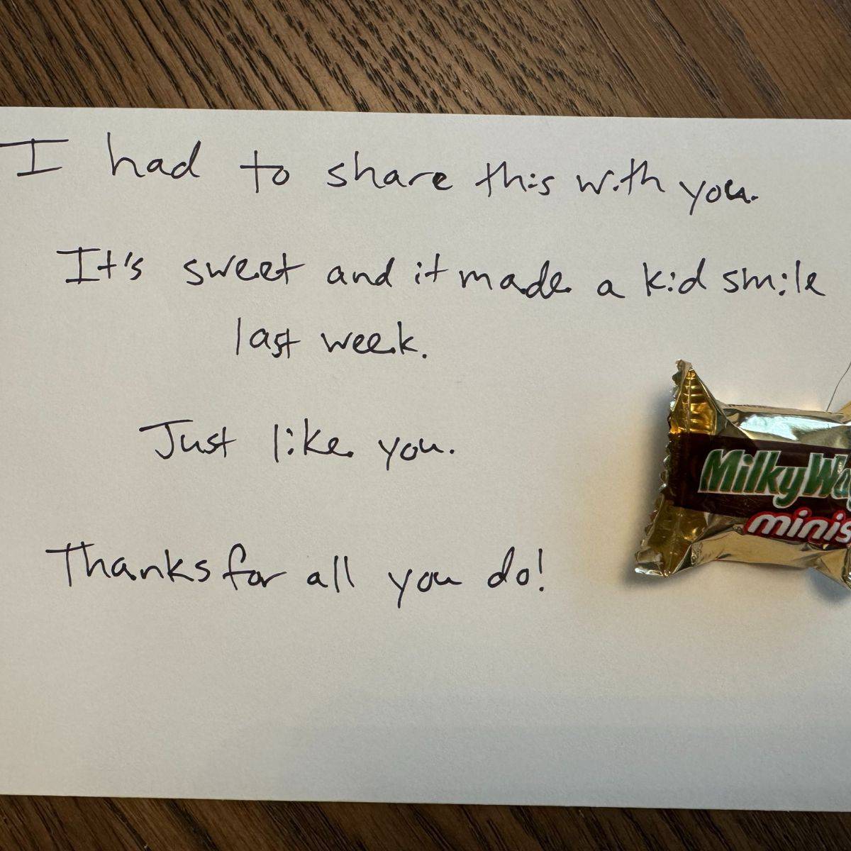 A mini Milky Way next to a handwritten note that reads, "I had to share this with you. It's sweet and it made a kid smile last week. Just like you. Thanks for all you do!"