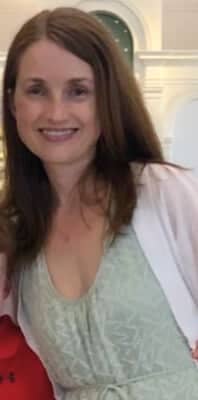 Lee smiling at the camera wearing a light green dress and white cardigan