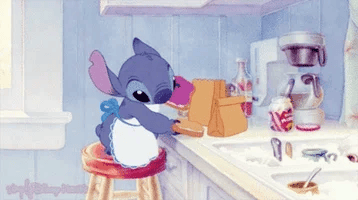 Stitch wearing an apron and passing out bagged lunches