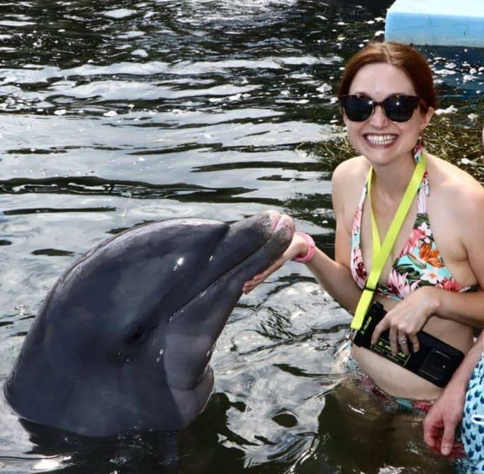 Lee excitedly touching a dolphin at a rescue center