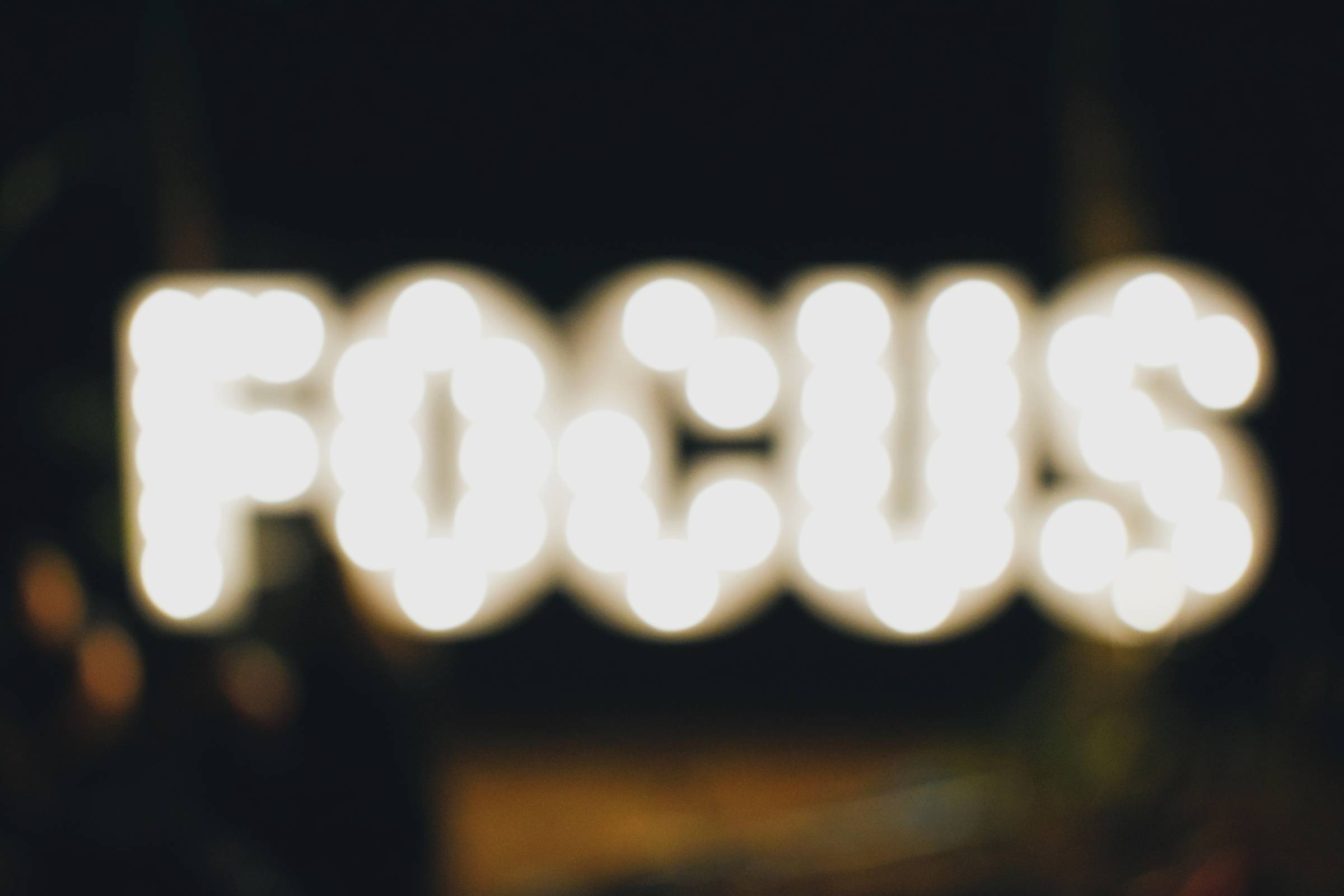 An out of focus lighted sign that says FOCUS. 