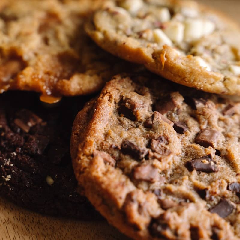 A pile of cookies sitting on top of a wooden cutting board
