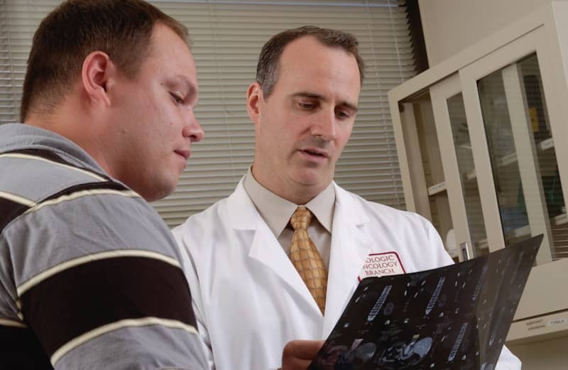 man in white lab coat holding black tablet computer