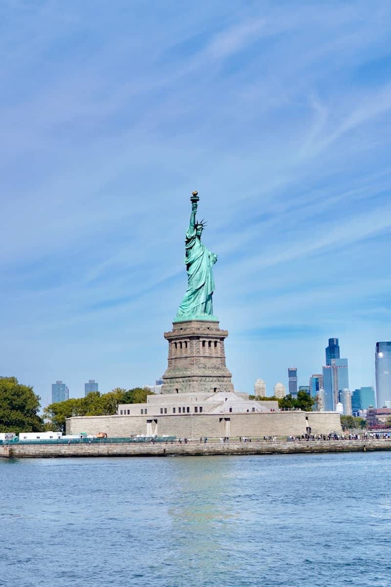The statue of liberty stands tall against a blue sky.