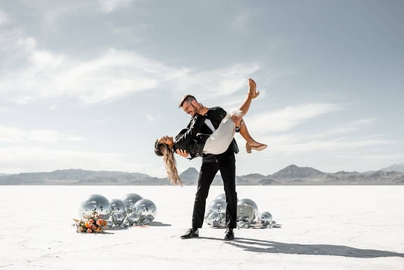A couple dances joyfully in a desert.