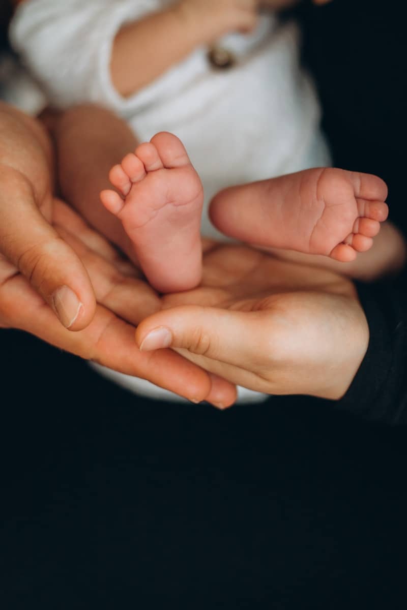 Adult hands gently hold tiny baby feet