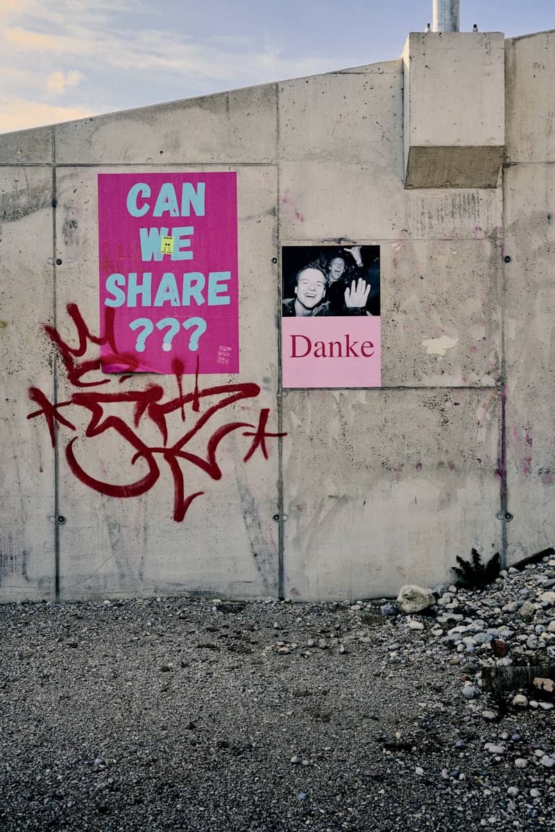 Concrete wall with "can we share ???" and "danke" posters.