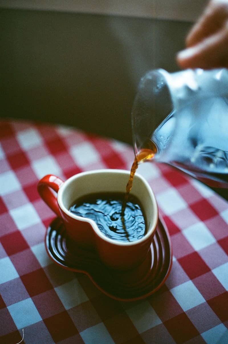 Coffee is being poured into a heart-shaped mug.