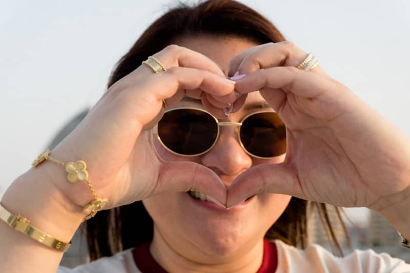 Smiling woman making a heart shape with her hands.