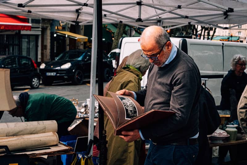 Man looking through an old photo album at a market.
