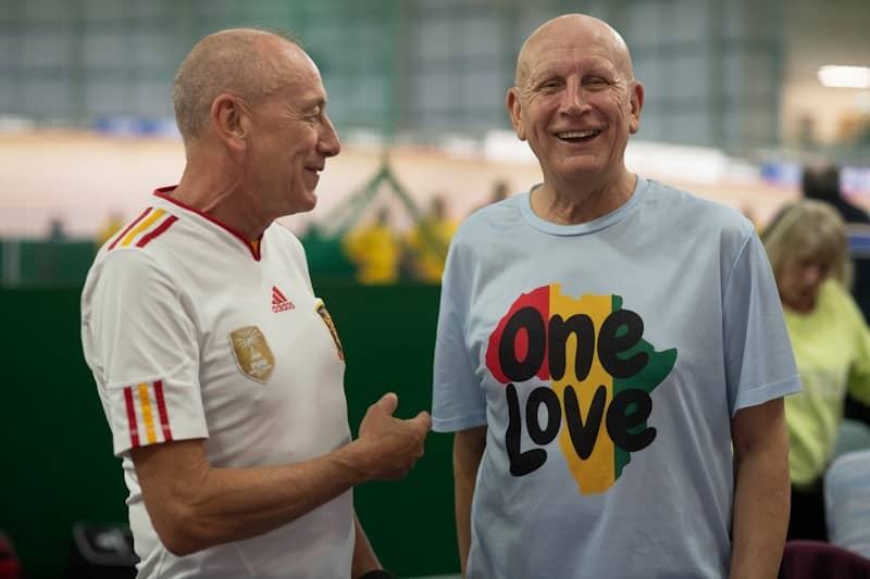 Two smiling men are talking to each other.