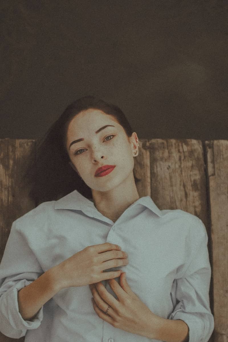 A woman with red lipstick lies on a wooden surface.