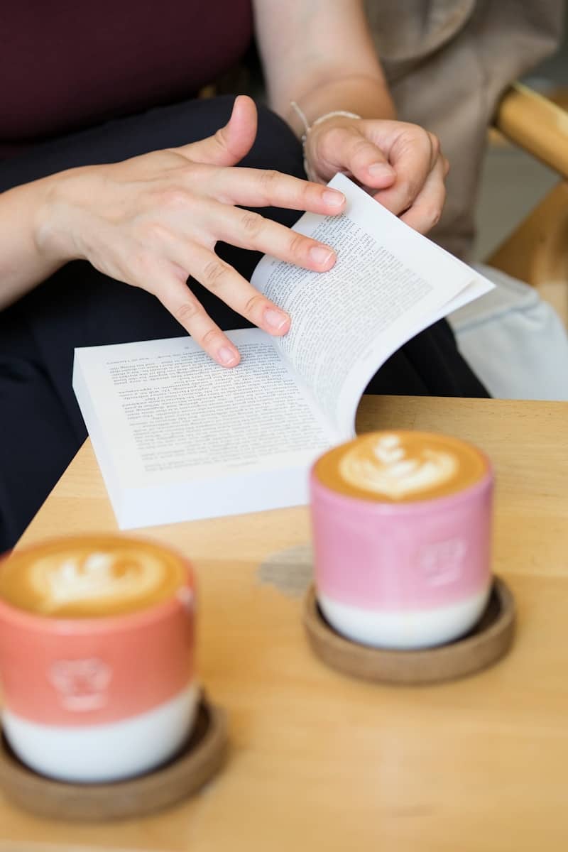 Person reading book, two latte art coffees