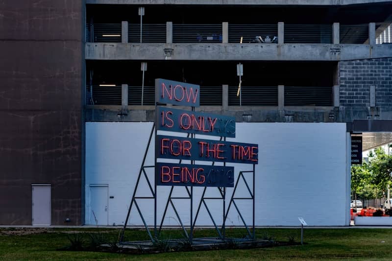 Neon sign reads "now is only for the time being"